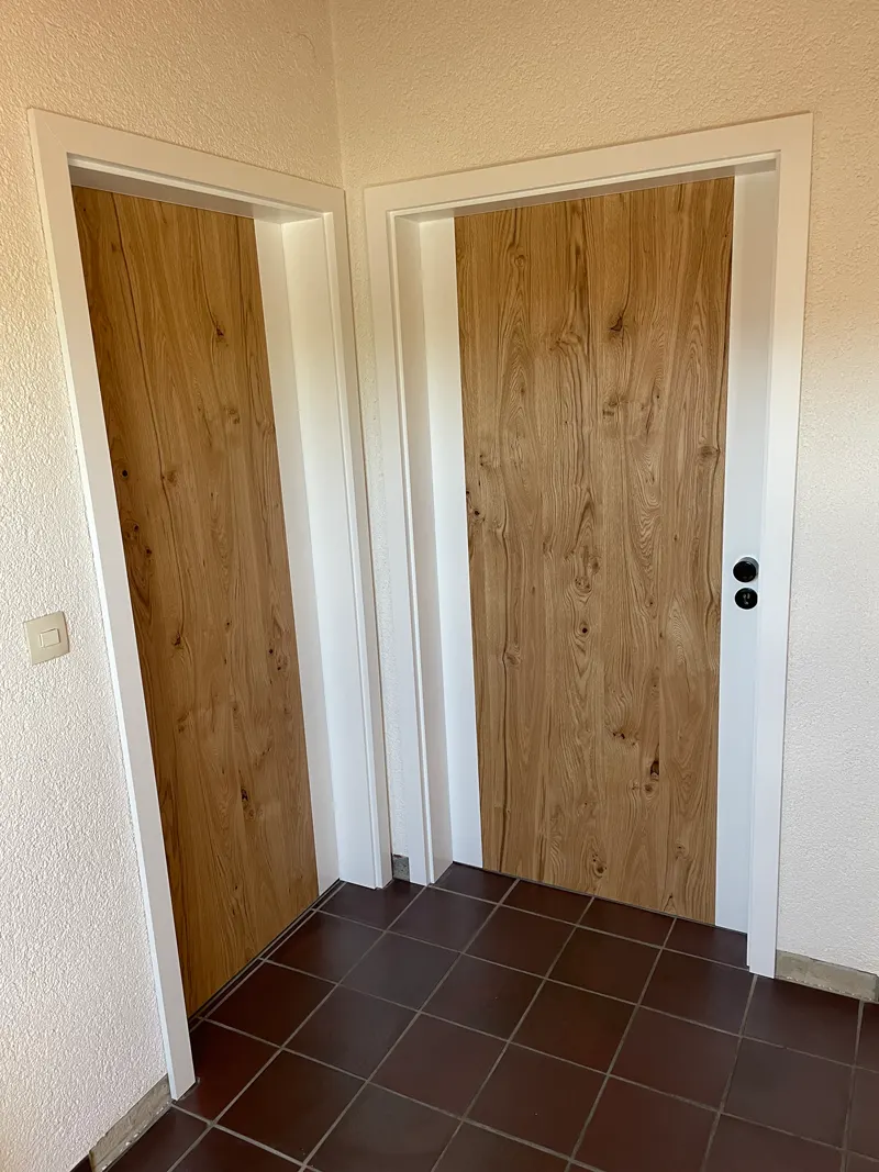 Zwei Türen in Holzoptik mit weißen Zargen und schwarzen Griffen